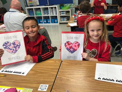 2 children hold up valentines they created