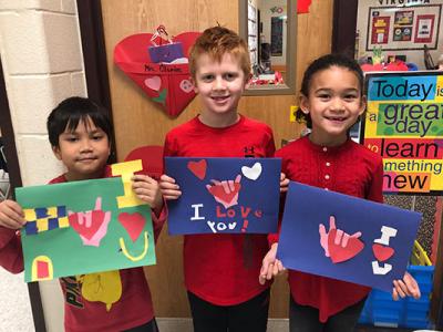 3 students hold up valentines they created